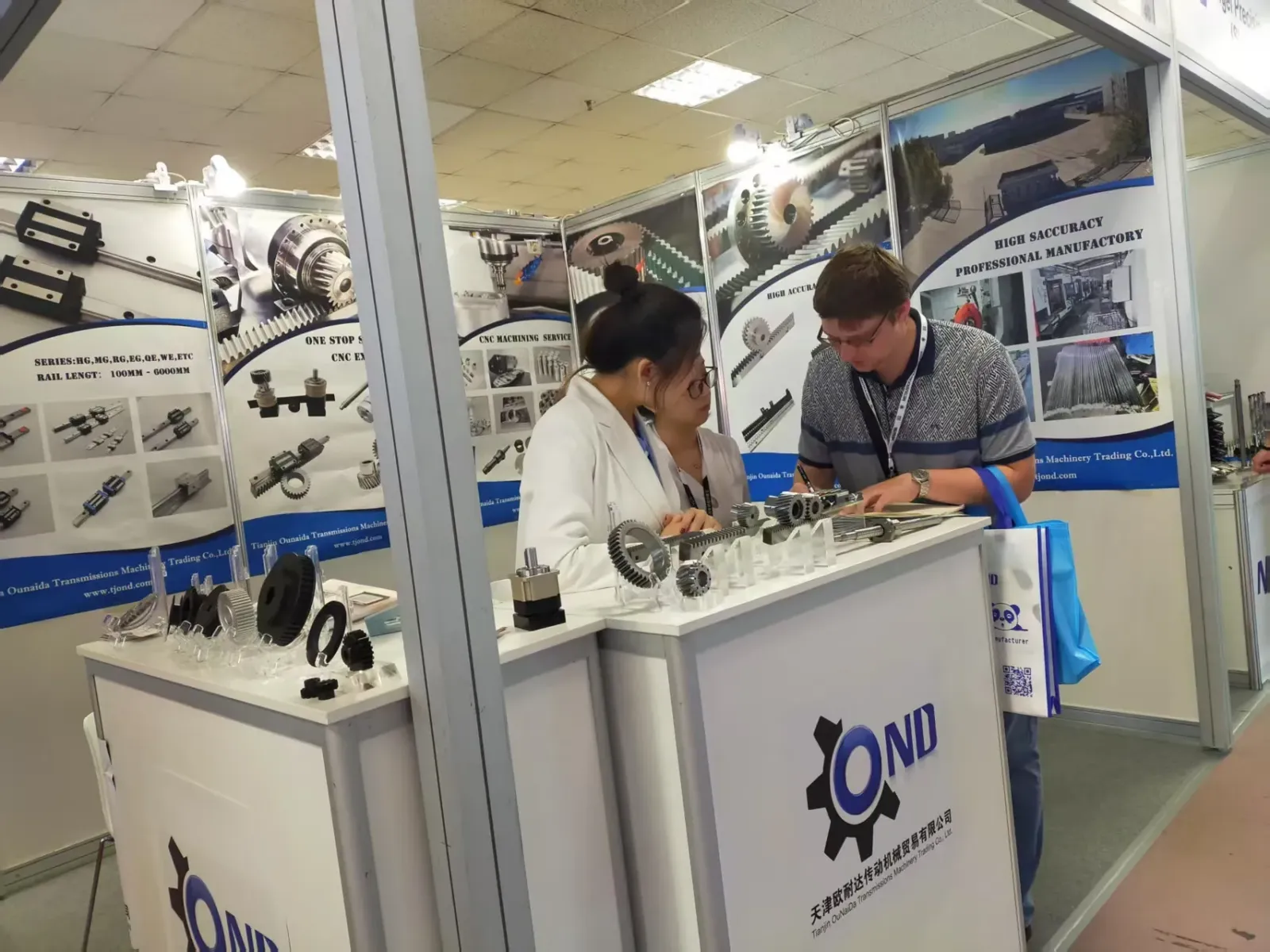 Discussing gear and gear rack samples with a visitor at the TJOND booth